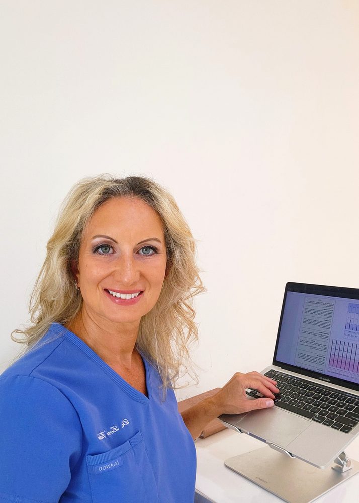 lori-desk-blue-scrubs Dr. Lori Kalie in blue scrubs reviewing lab results at her desk