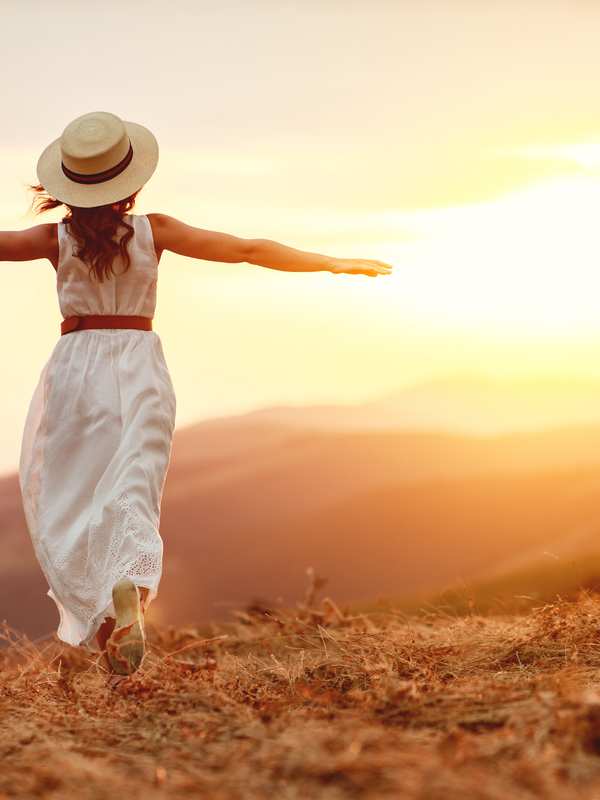 A woman with arms spread wide at a mountain sunset, representing the freedom and energy that returns once root causes are addressed A woman with arms spread wide at a mountain sunset, representing the freedom and energy that returns once root causes are addressed