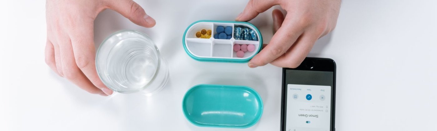 Hands sorting professional-grade supplements into a pill organizer